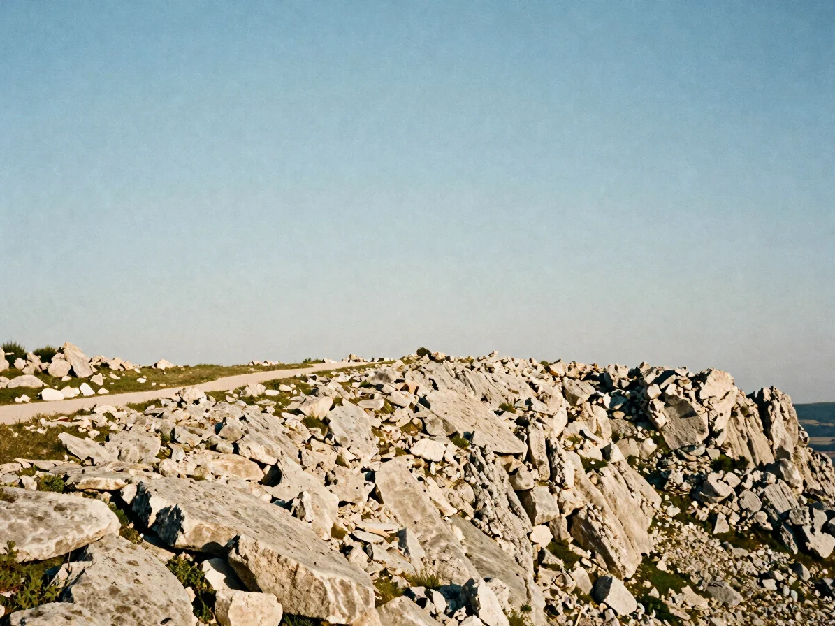 Landscape photograph of a limestone ridge line under clear sky, a narrow footpath running along the crest, soft morning